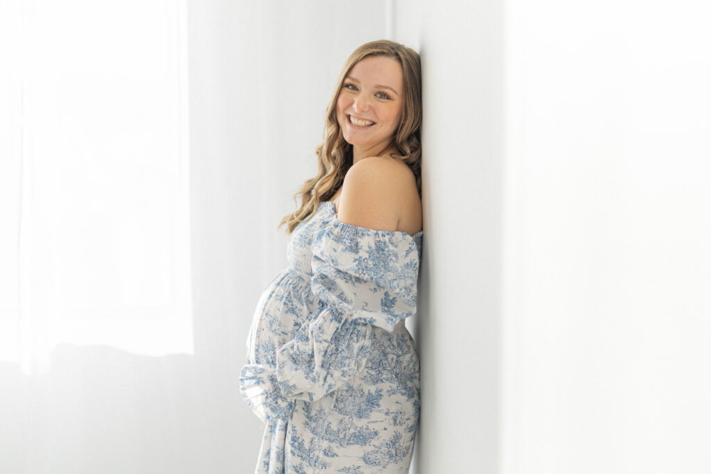 knoxville portrait photographer. pregnant women leaning against white wall in blue dress.