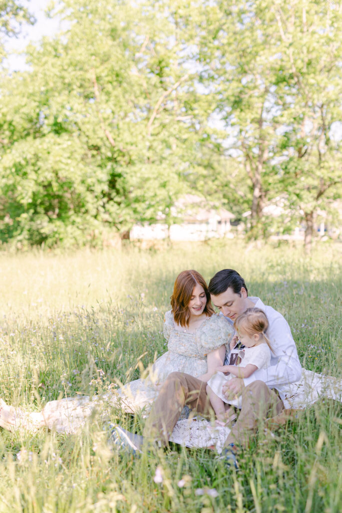 family sitting in a field of green. knoxville maternity photographer