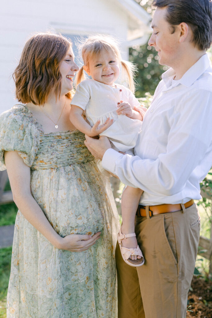 knoxville maternity photographer. mom, dad, and little girl in the middle being cuddle and kissed